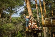 Father and child embrace adventure on a forest zipline in Cercedilla, Spain.