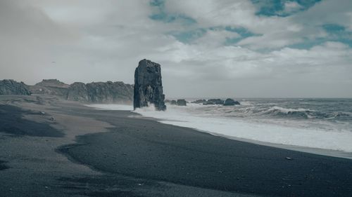 Free Stunning black sand beach with rocky formations and crashing waves in Iceland. Stock Photo