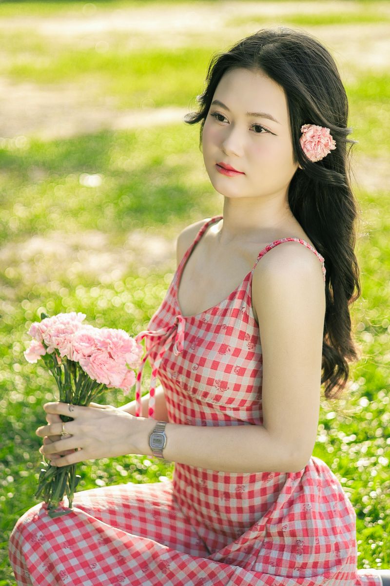 Young woman in a red gingham dress holding flowers