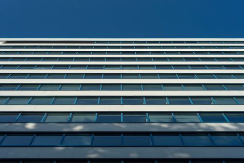 Free A low-angle view of a modern building facade under a clear blue sky. Stock Photo