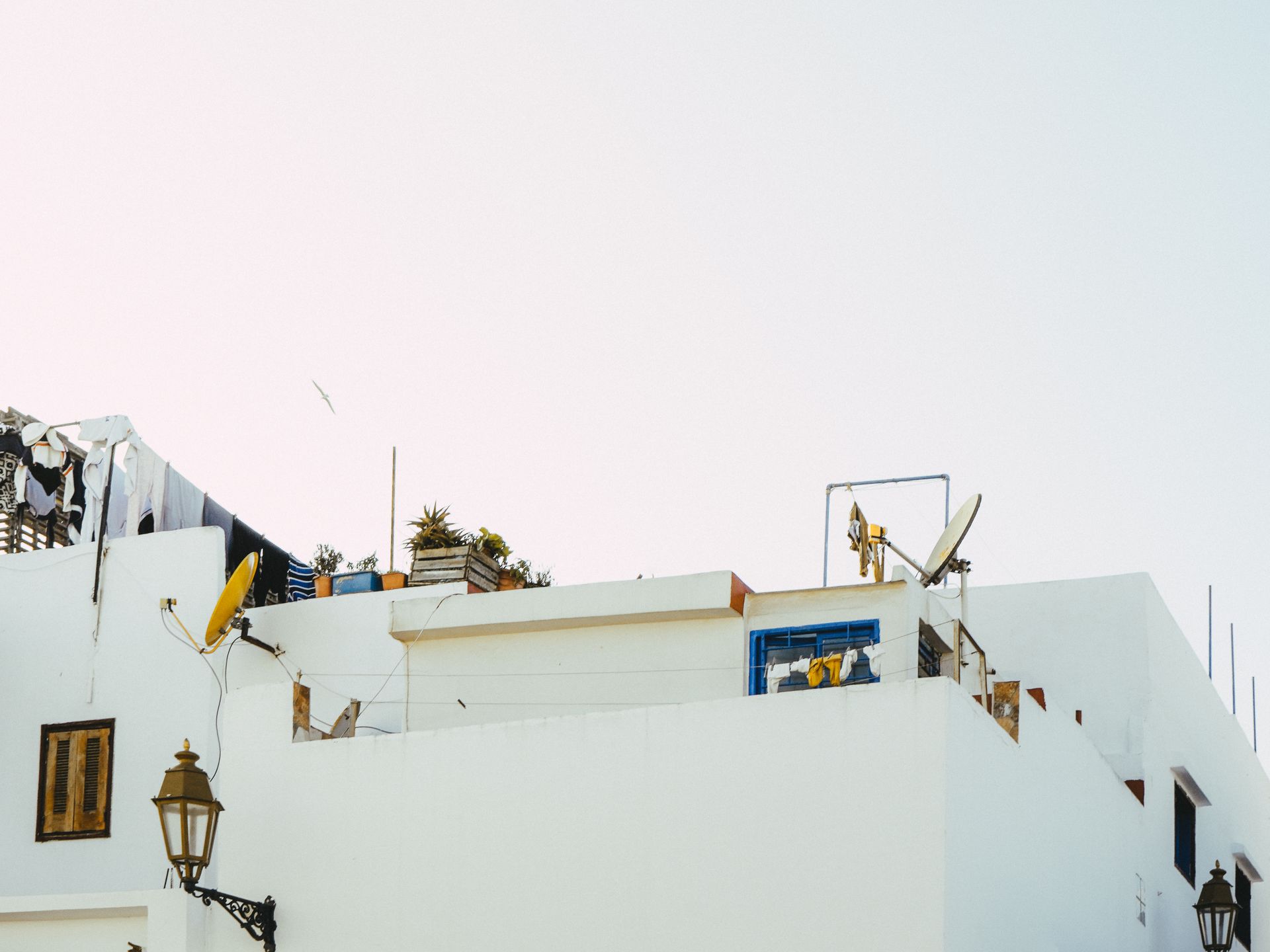 View of a whitewashed building rooftop with antennas and laundry under clear sky.