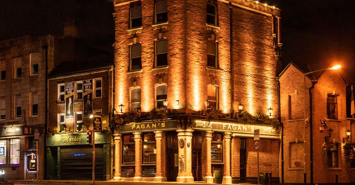 A warm-lit, historic brick pub building captured at night on a quiet city street.