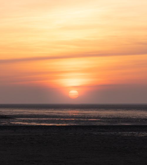Free Stunning sunset view over the Wadden Sea in Cuxhaven, Germany, with warm orange hues creating a tranquil scene. Stock Photo