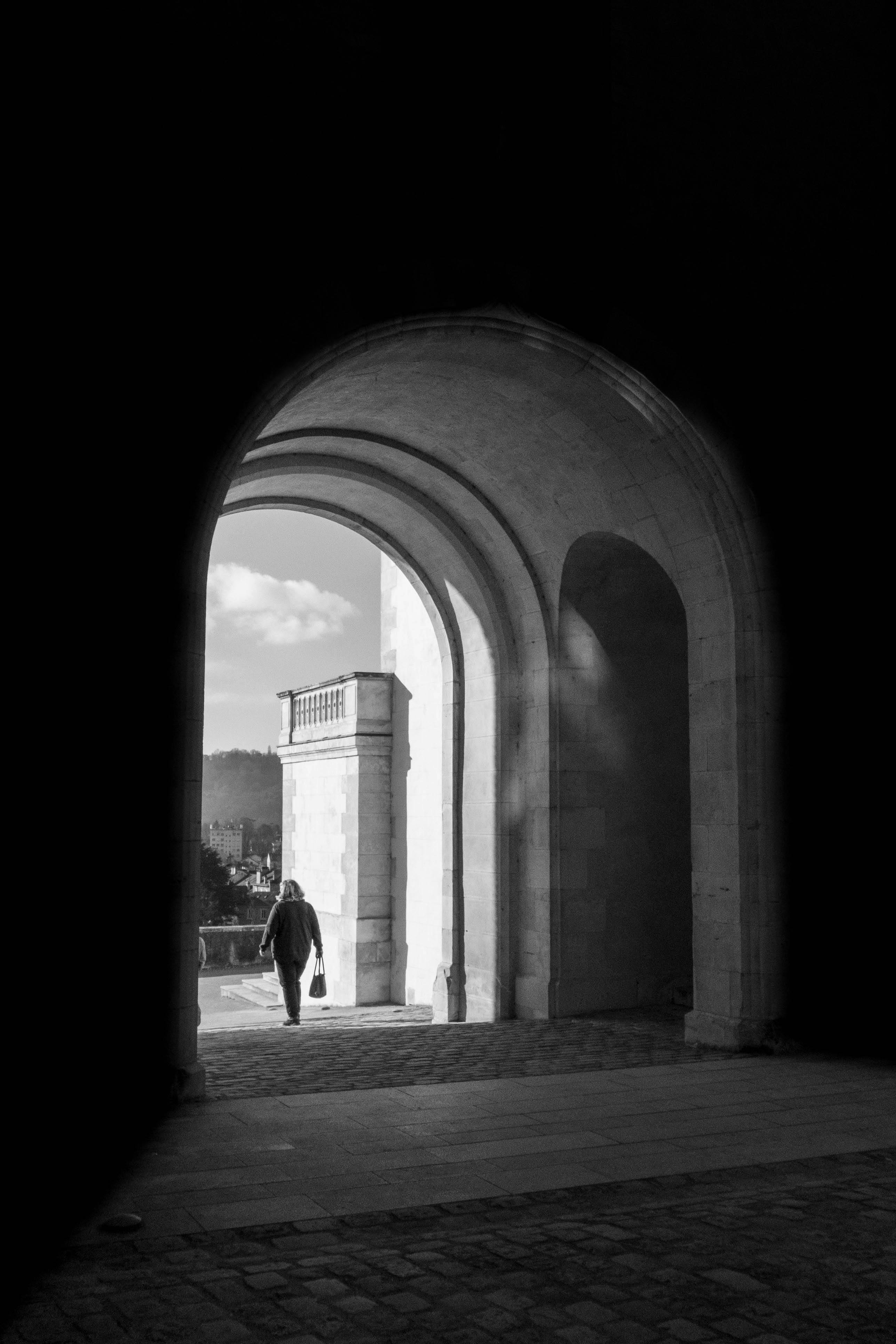 A captivating black and white scene of an archway in Pau, France, with a solitary figure.
