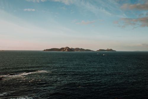 Free Peaceful ocean scene with islands under a colorful sunset sky, ideal for nature and travel themes. Stock Photo