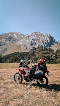 A motorbike parked in a stunning mountain vista on a sunny day.