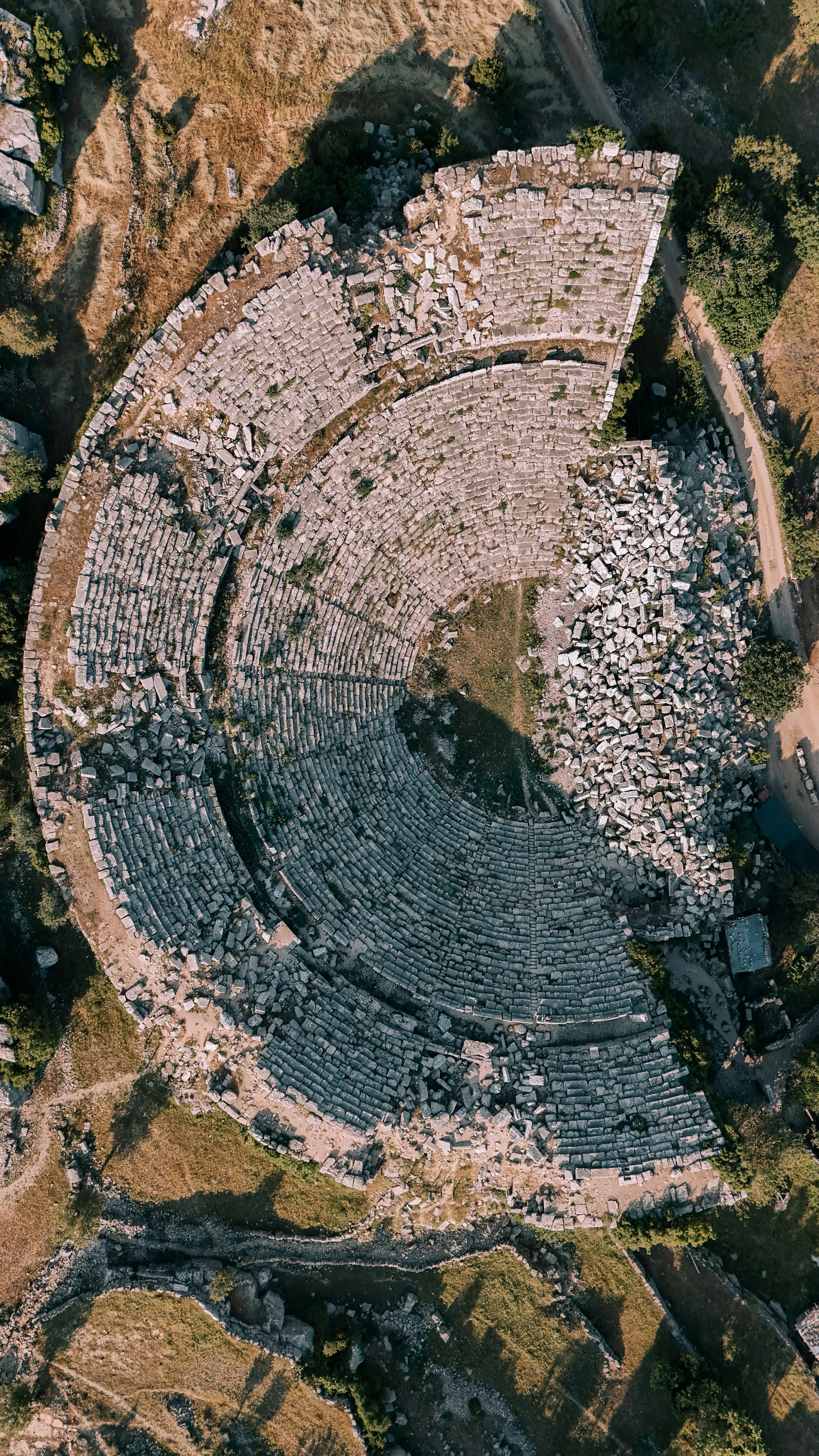 Free A captivating aerial shot of ancient amphitheater ruins in a natural landscape. Stock Photo