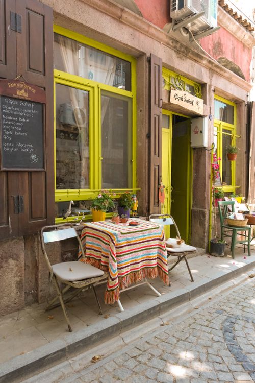 Free Colorful cafe with a charming facade on a cobblestone street in Ayvalık, Türkiye. Stock Photo