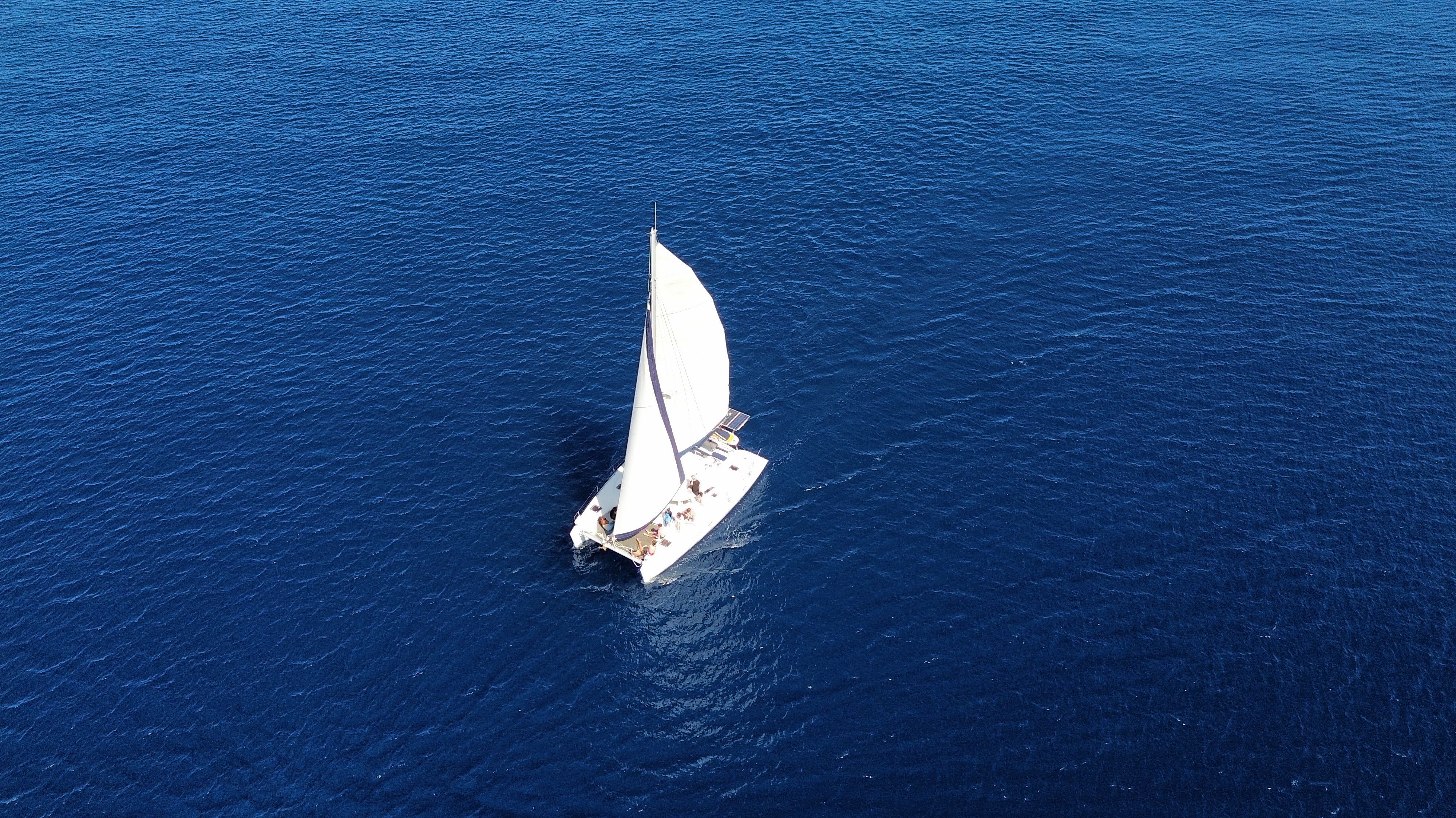 Stunning Waikiki Private Sunset Sail Romantic and Private Review: The Ultimate Hawaiian Sunset Experience Review 2026 - Aerial shot of a sailboat navigating through the vast deep blue sea, creating a serene image of ocean travel.