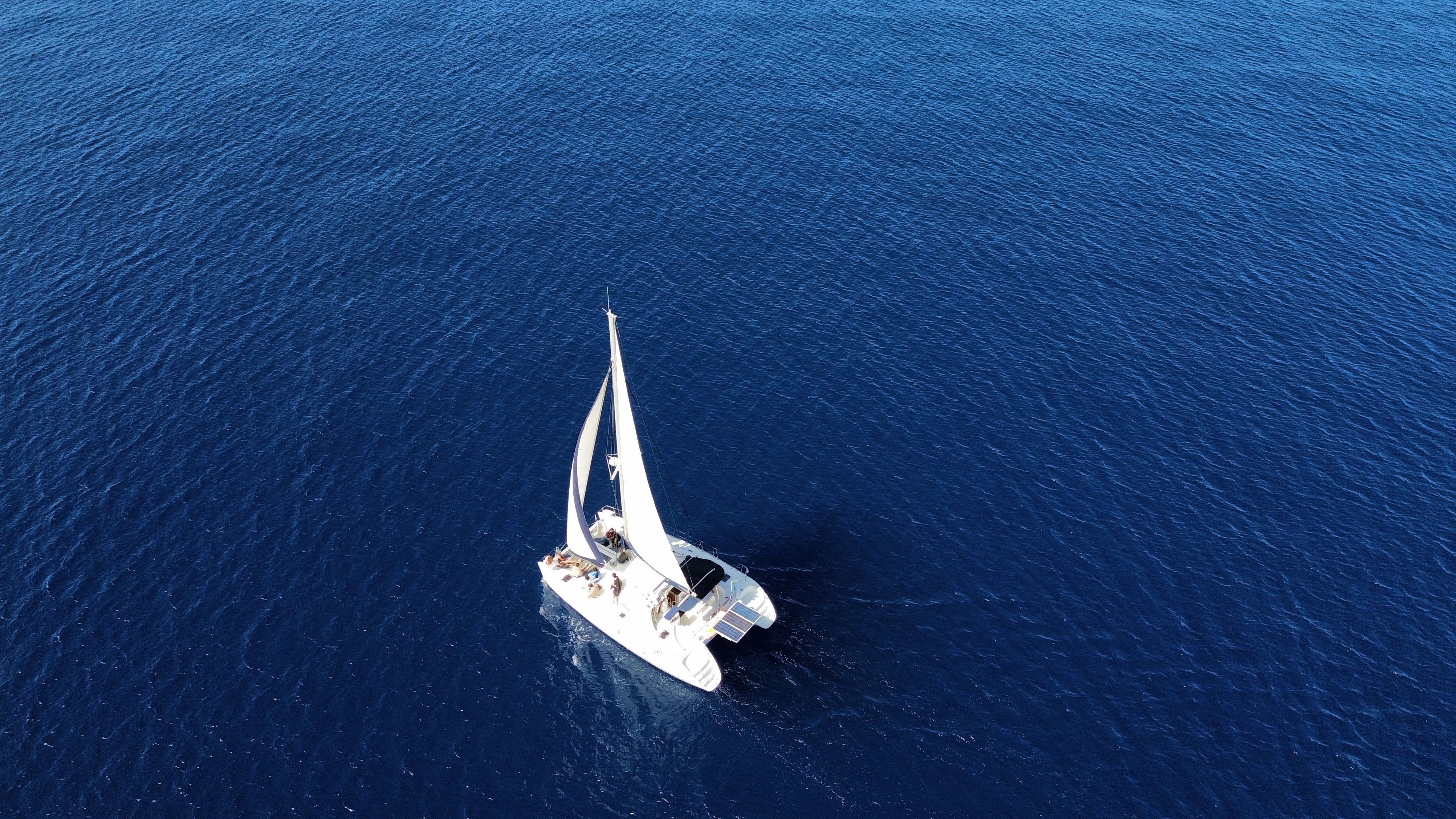 Unforgettable Small Group Yacht Sunset Cruise from Oahu Review: The Ultimate West Oahu Sunset Experience Review 2026 - Stunning aerial view of a sailboat navigating the vast, deep blue ocean waters.