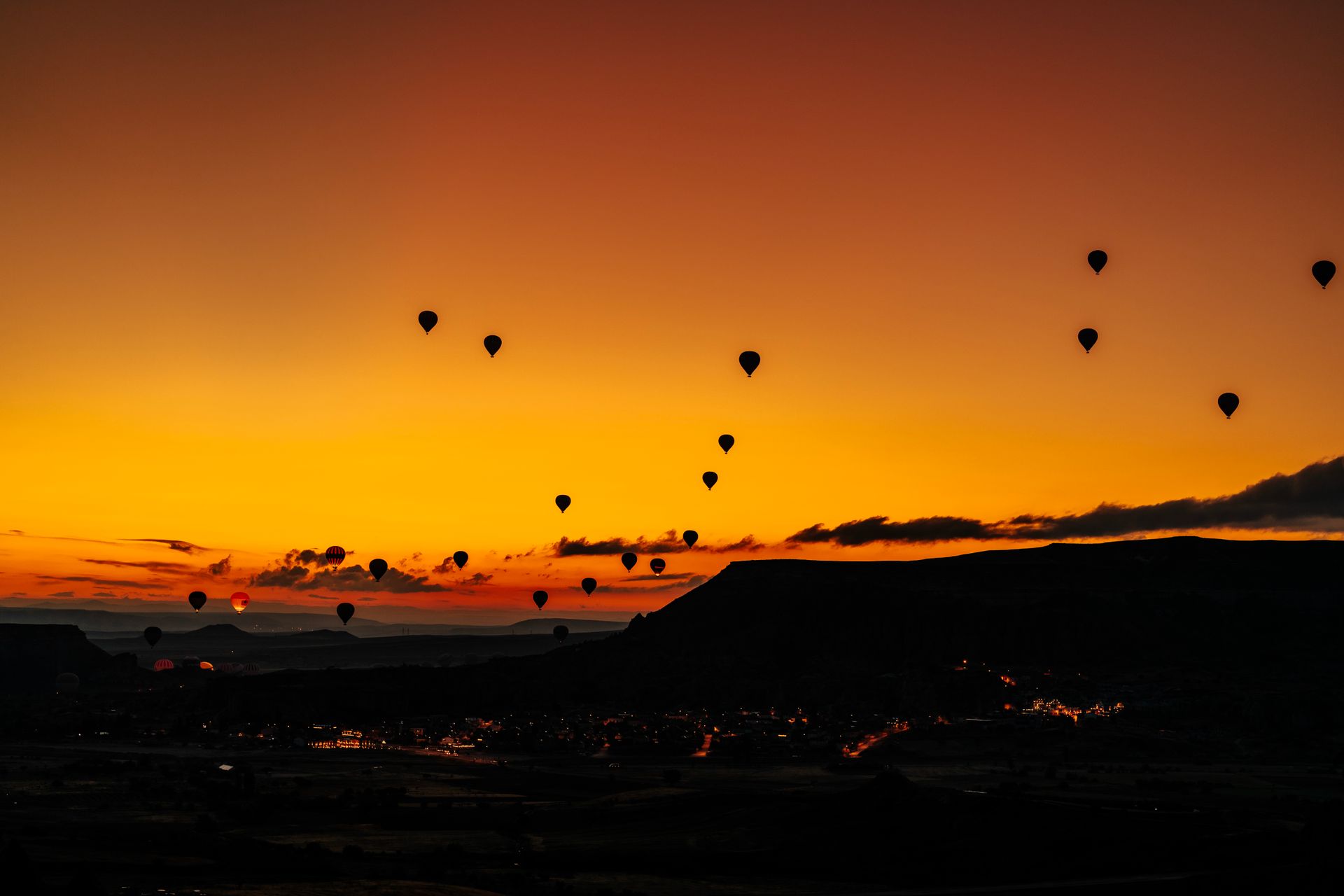 Stunning view of hot air balloons floating over Cappadocia during sunrise, creating a dramatic silhouette.