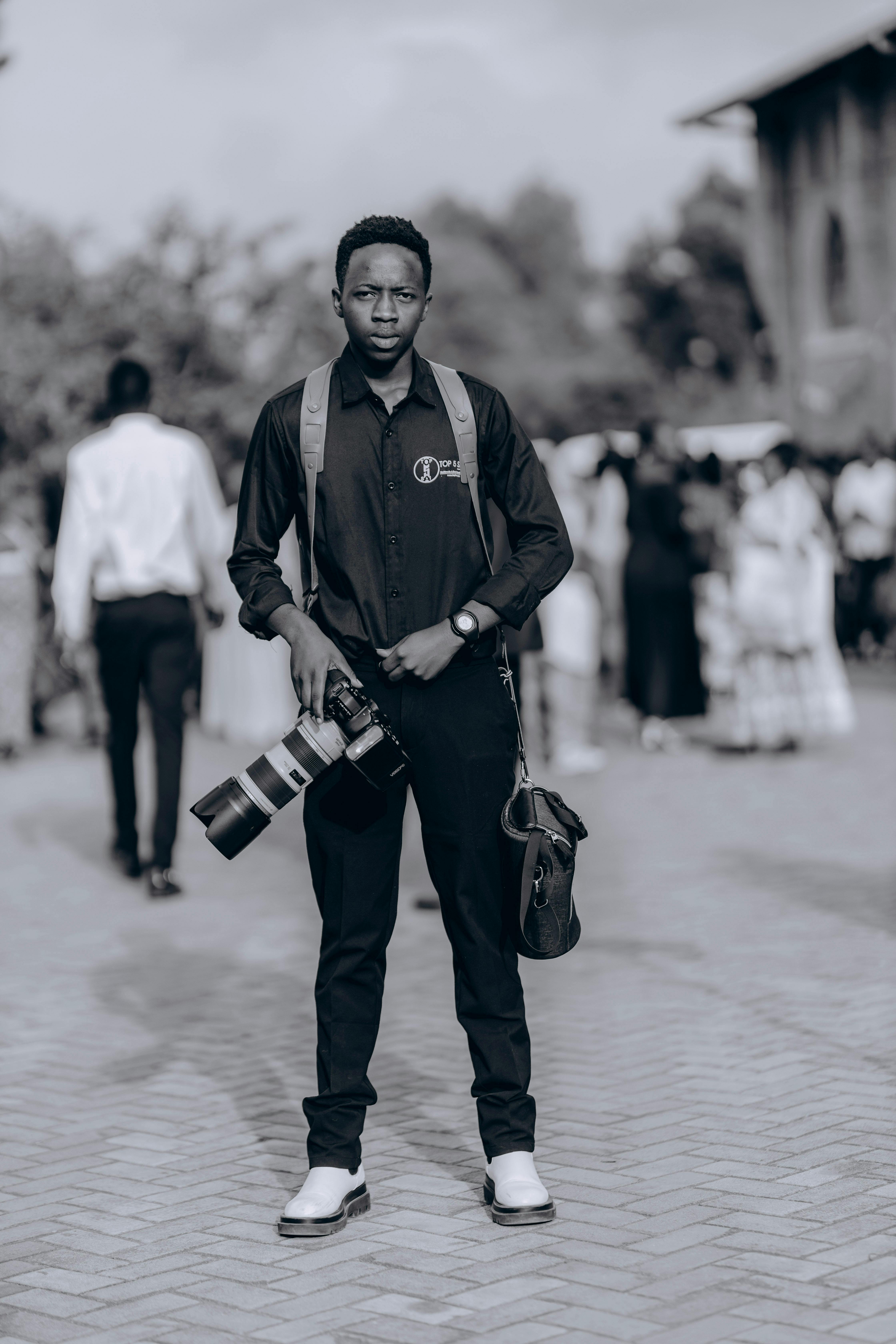 A professional photographer with camera gear standing outdoors at an event.