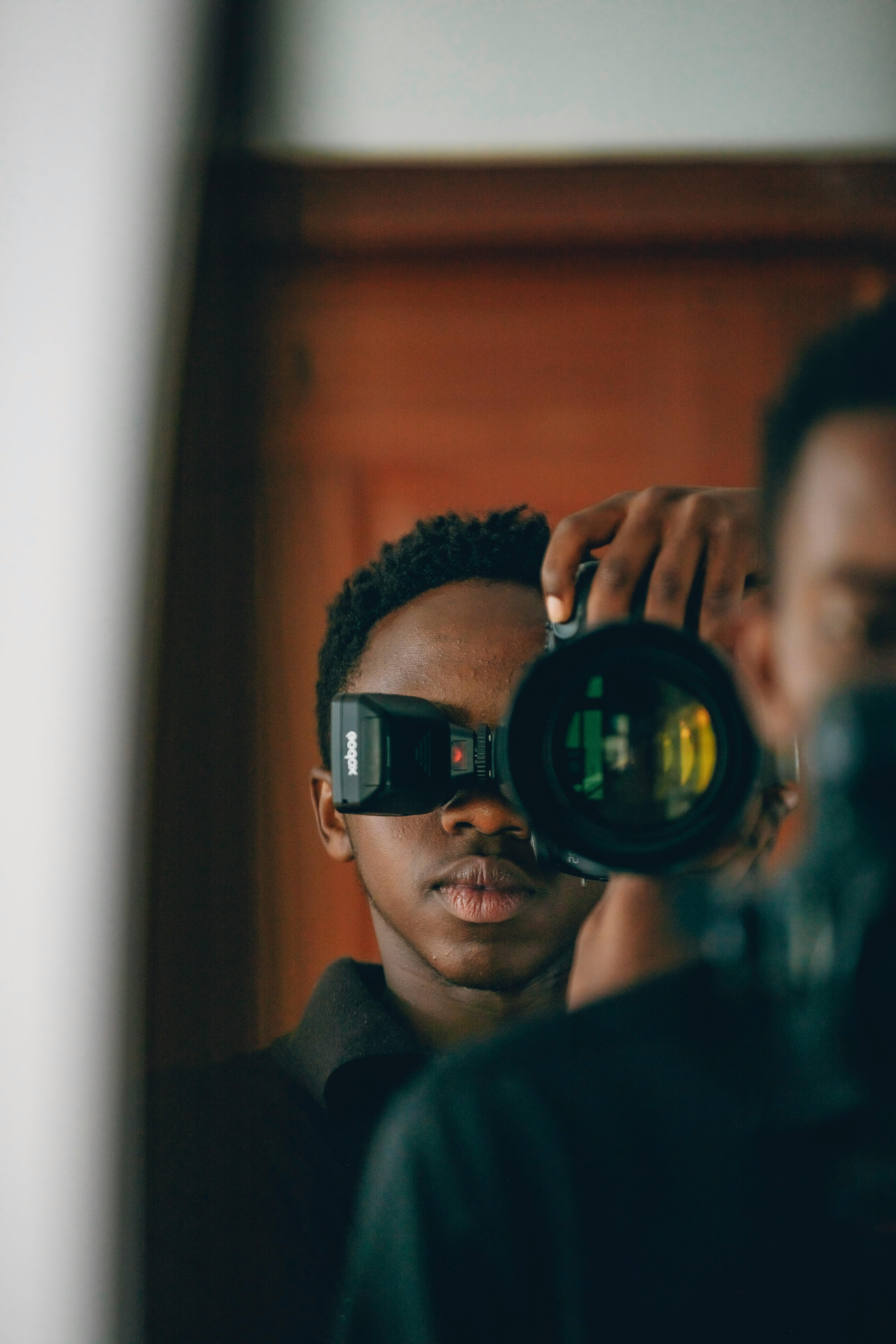 Self-portrait of a photographer capturing reflection in a mirror with camera.