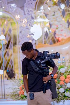 A professional videographer capturing a wedding scene, surrounded by beautiful floral arrangements and elegant decor.