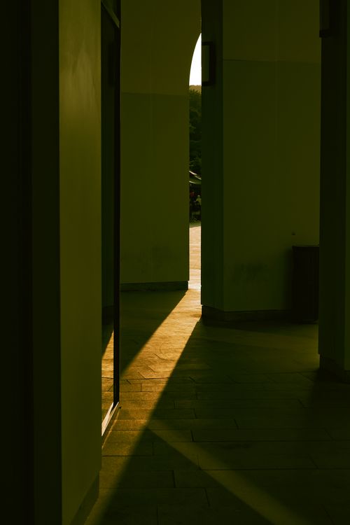 Free Warm sunlight creates dramatic shadows in a hallway with an archway. Stock Photo