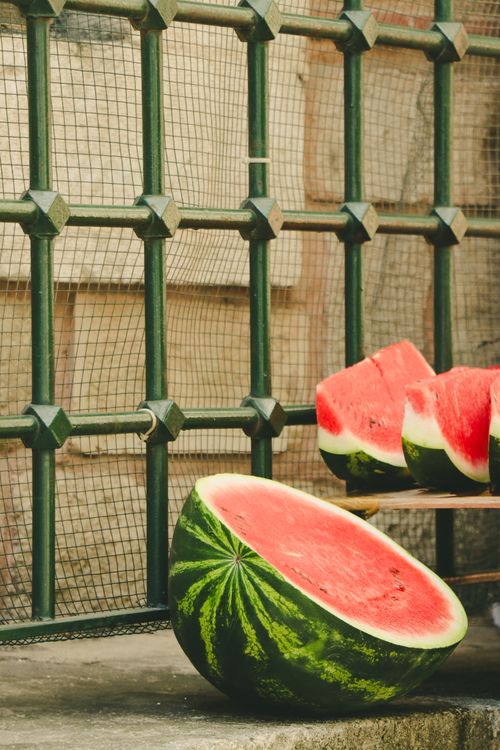 Free Fresh watermelon slices displayed on a ledge by an ornate fence, capturing a sunny day in Istanbul. Stock Photo
