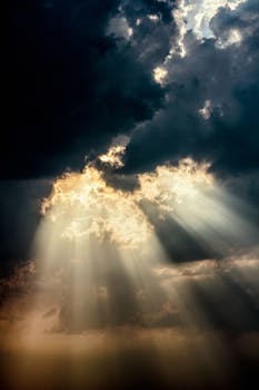 Sun rays piercing through dark clouds create a dramatic sky scene.