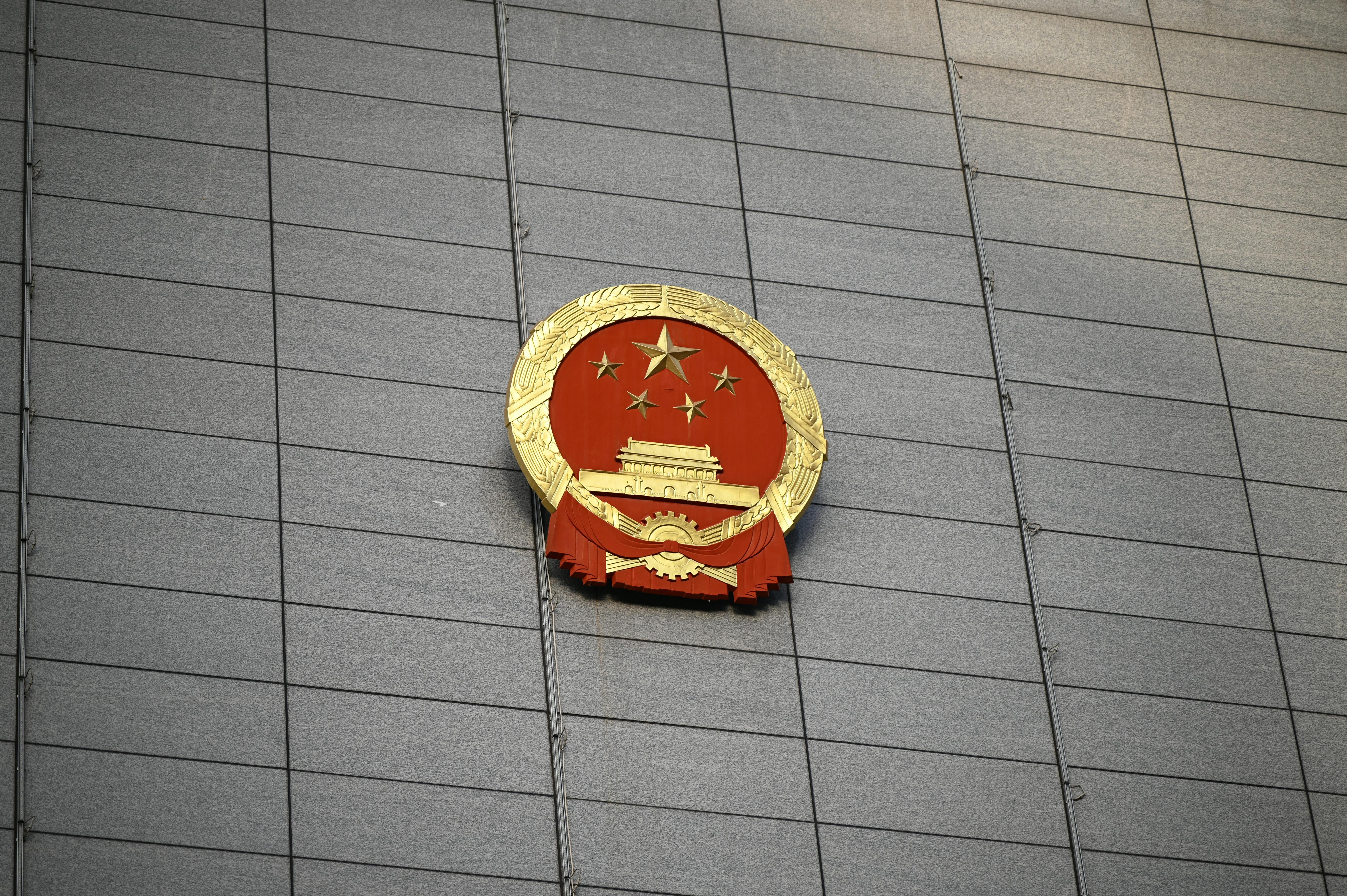 Free Close-up of the Chinese national emblem on a large concrete building facade, symbolizing government presence. Stock Photo