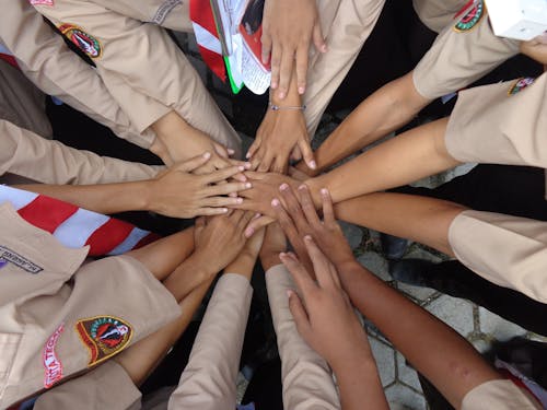 Crop military ethnic females stacking hands