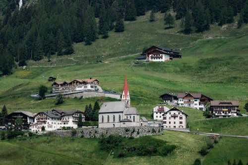 Free Scenic view of an Austrian village with a historic church amid lush hills and forest. Stock Photo