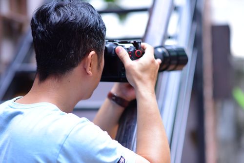 Free A photographer using a camera outside, focusing on capturing a scene. Stock Photo