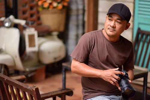 Free A male photographer sits holding a camera in a vintage styled outdoor setting. Stock Photo