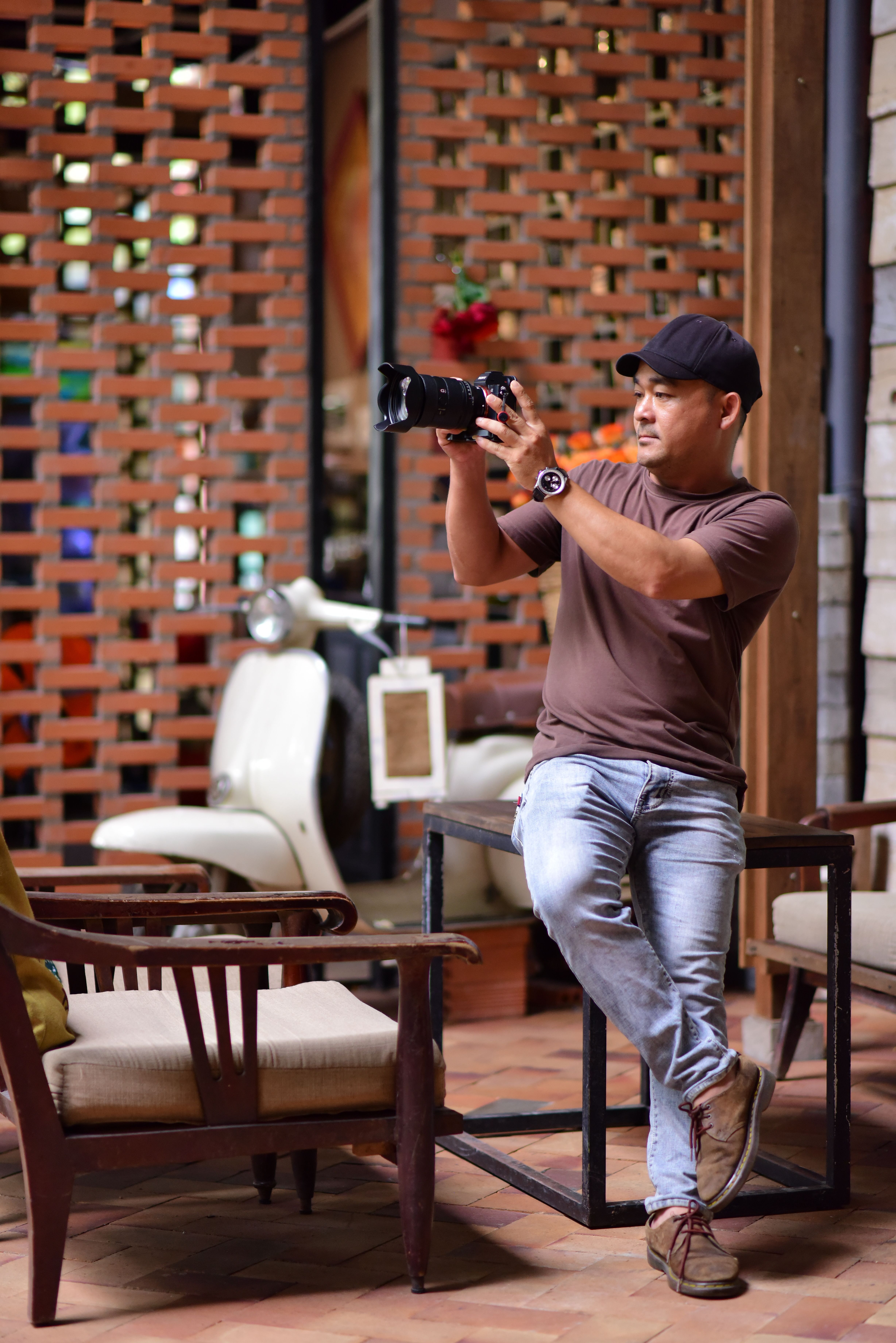 Adult male photographer using a DSLR camera indoors. Casual setting with modern decor.