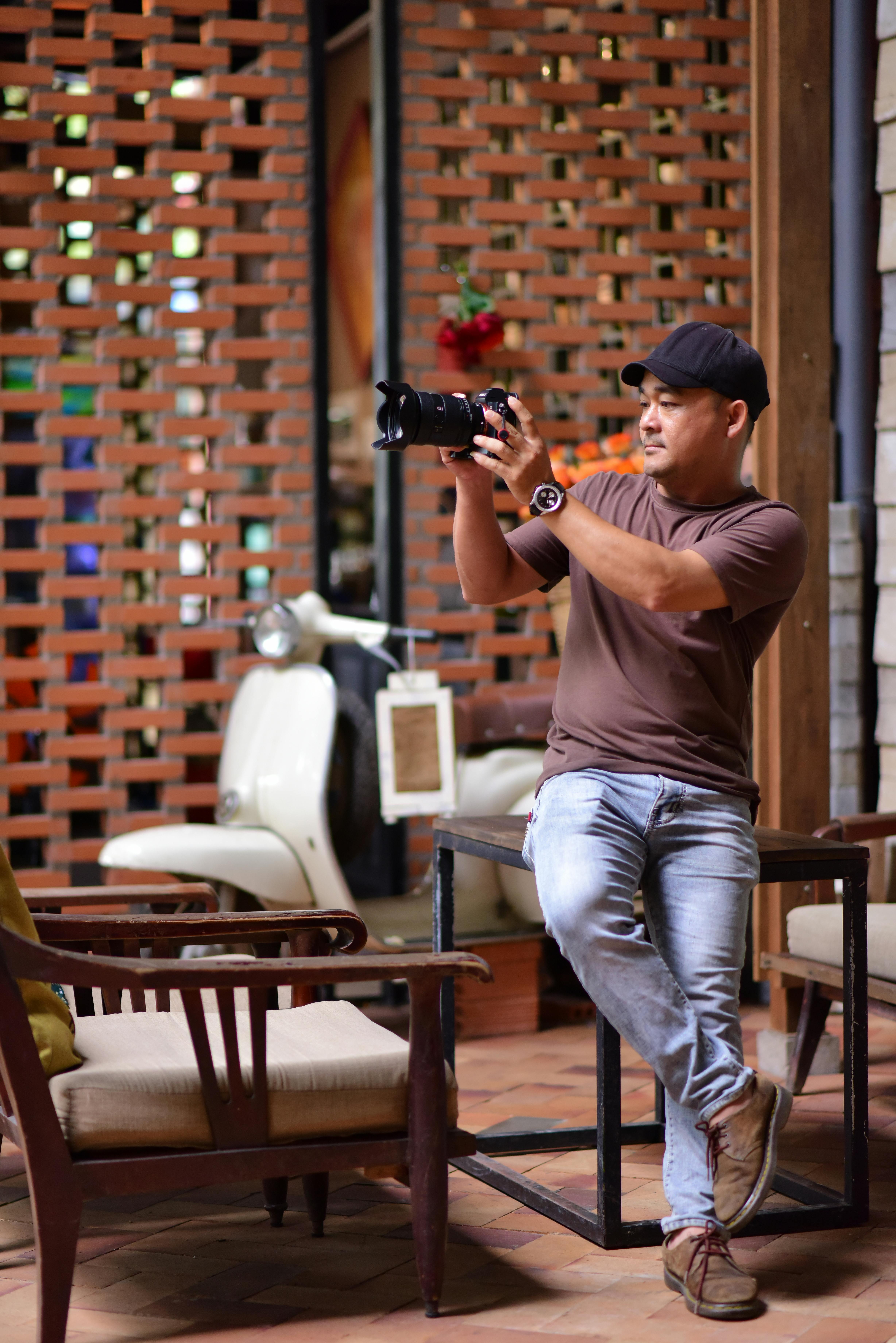A man casually photographing inside a stylish coffee shop with vintage decor.