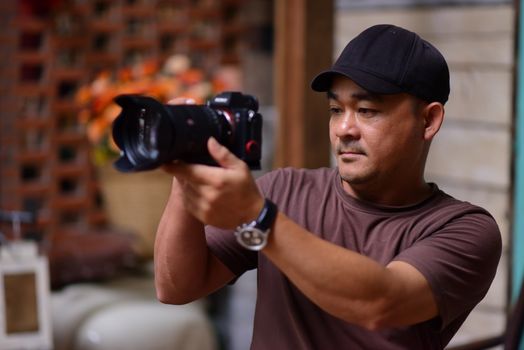 Man holding DSLR camera indoors focusing intently. Captures a precise and attentive moment in photography.