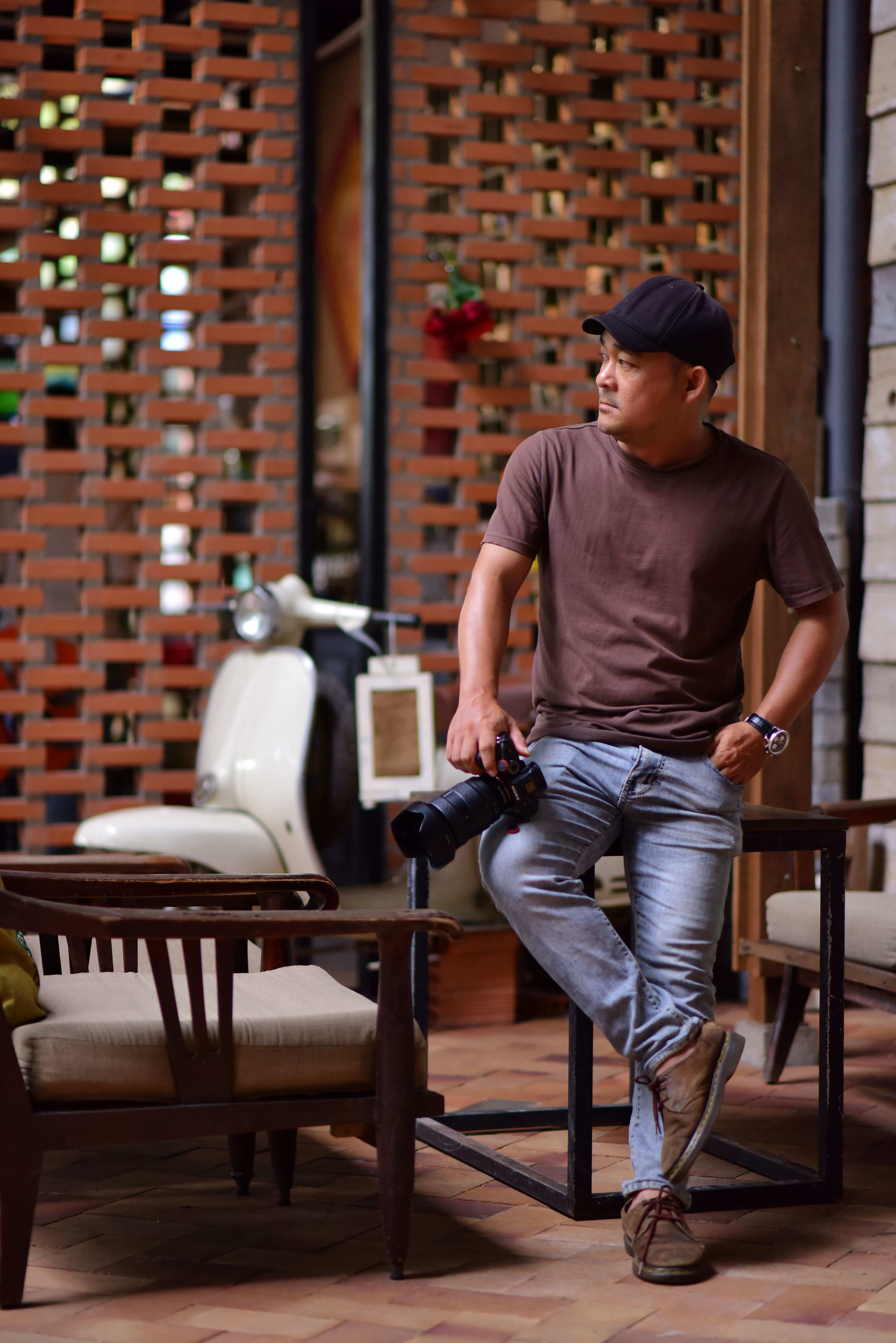 Casual male photographer holding a camera indoors, showcasing relaxed style and creativity.