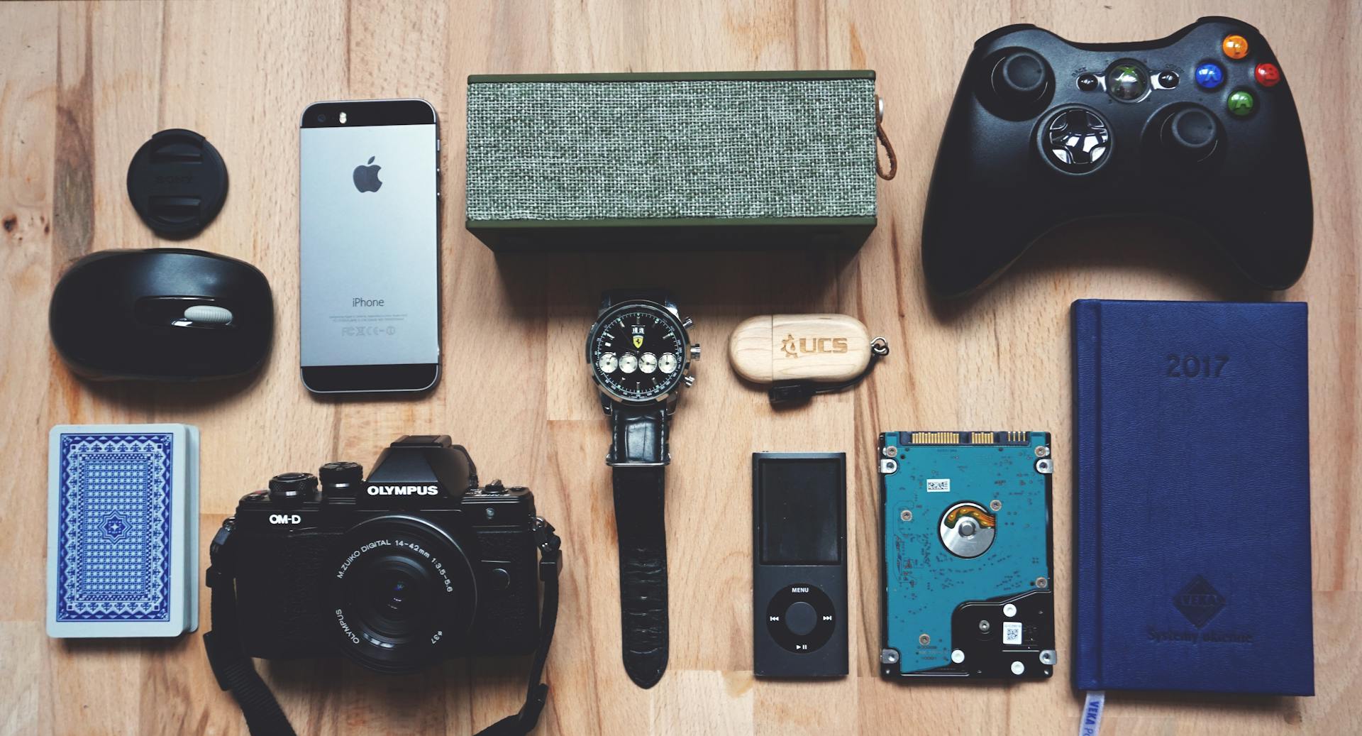 Flat lay of various modern gadgets, accessories, and tech items on wooden surface.