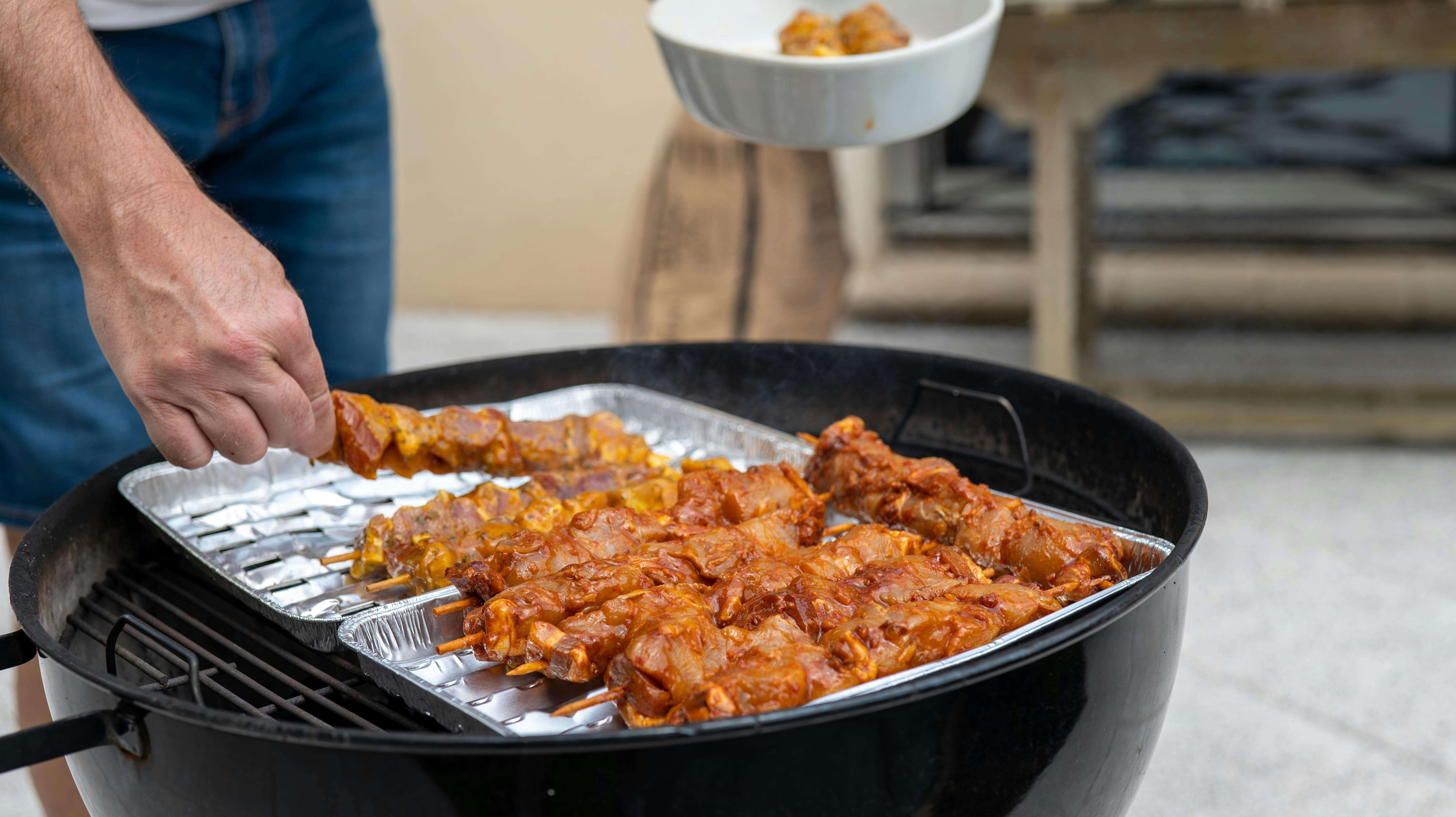Free Delicious meat skewers grilling at outdoor barbecue event. Perfect for summer parties. Stock Photo