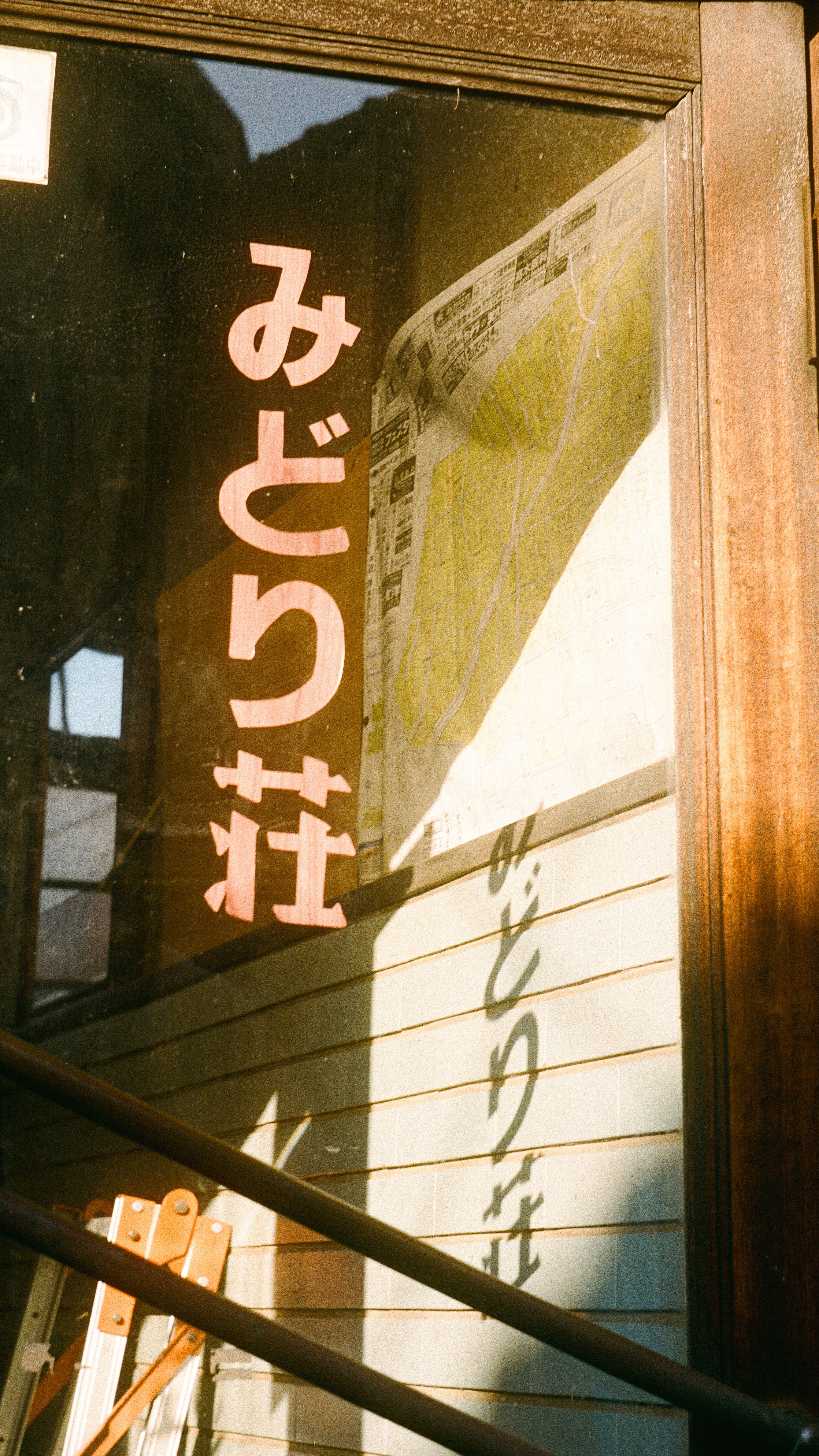 A sunlight-lit vintage door with Japanese text, reflecting a nostalgic ambiance.