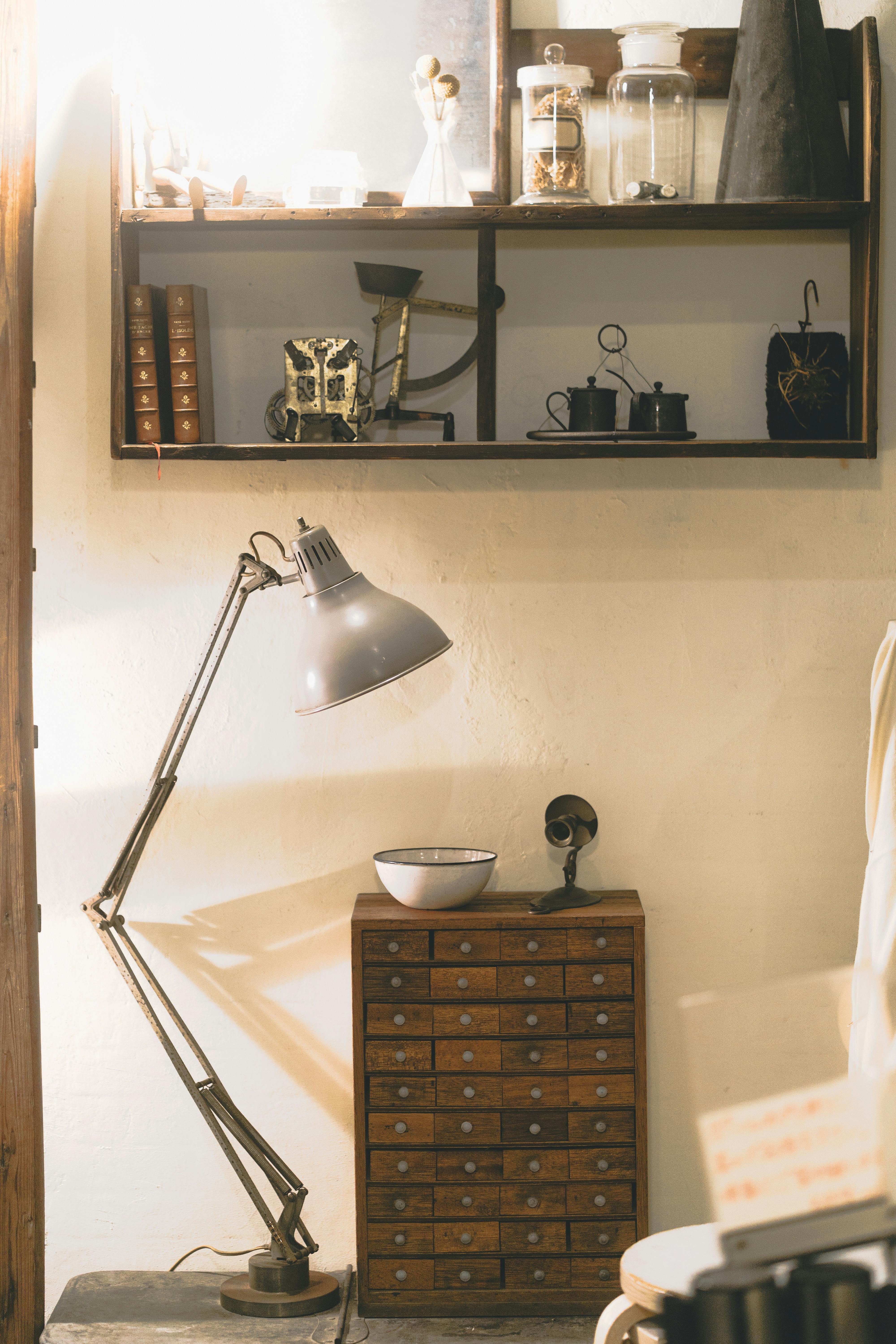 A warm, vintage interior with an industrial lamp, vintage shelves, and a wooden drawer unit.