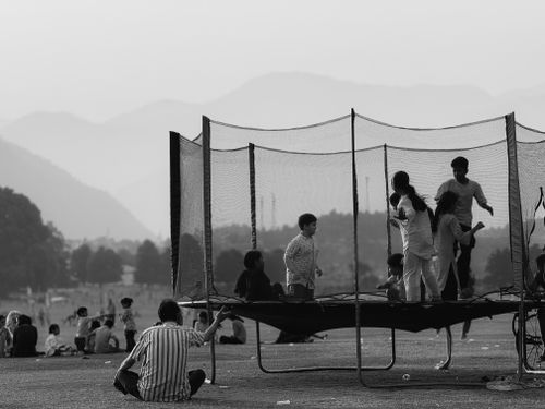 Free A group of children enjoy playing on a trampoline in an outdoor park with a mountain backdrop. Stock Photo