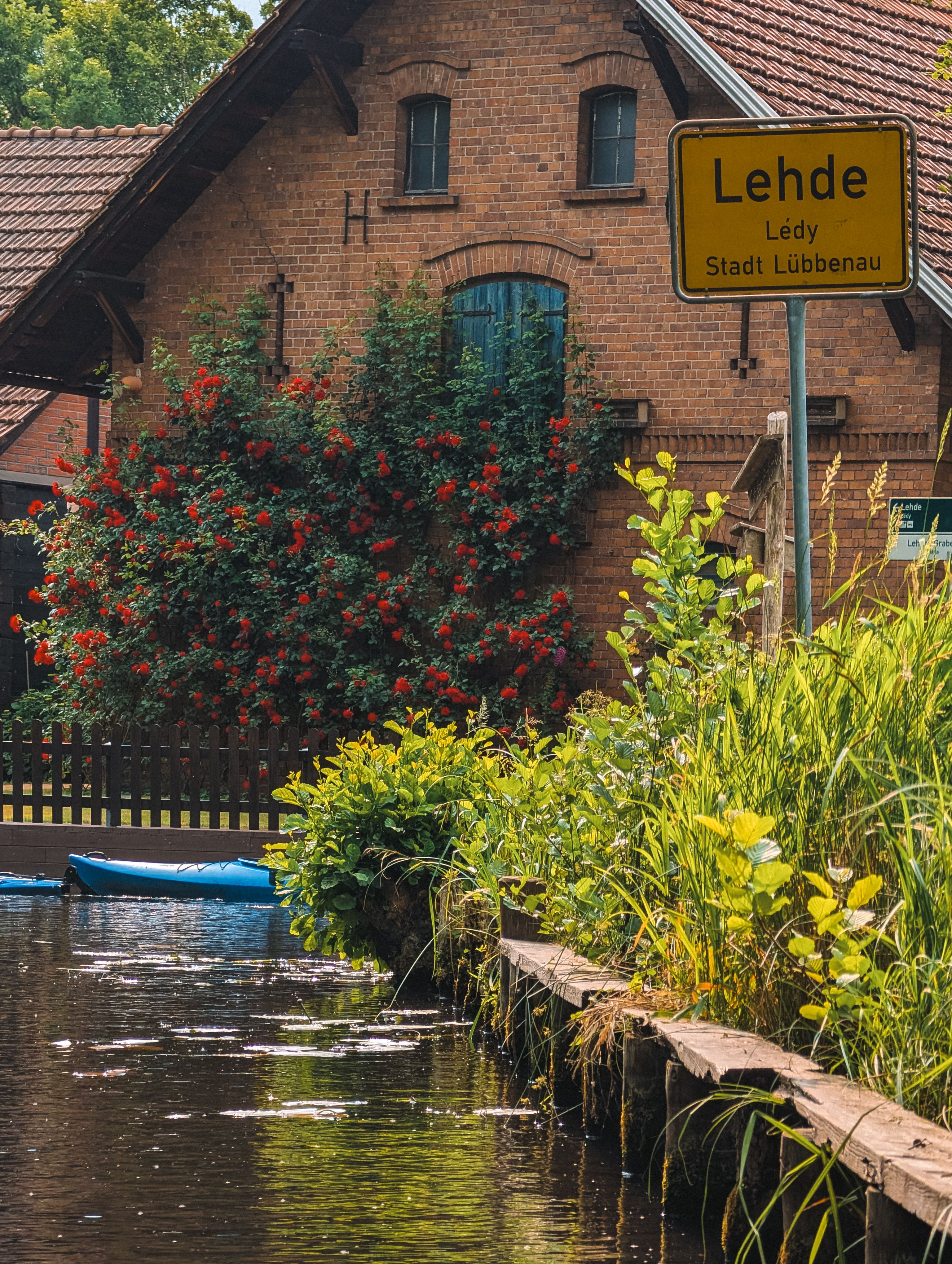 Tranquil canal scene in Lehde, Lübbenau with lush flora and classic brick architecture.