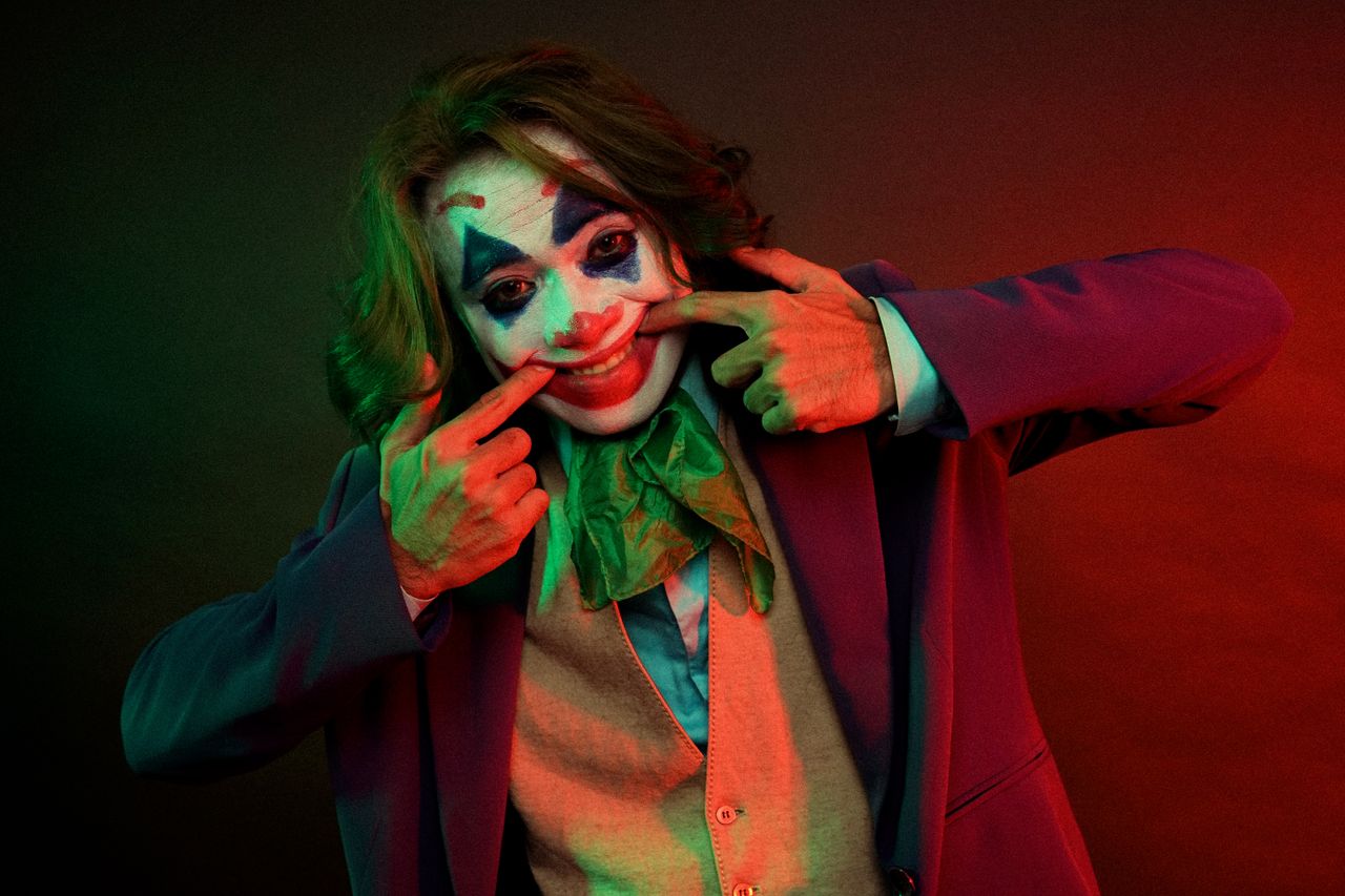 dramatic male clown with painted face grimacing smile pulling mouth wi
