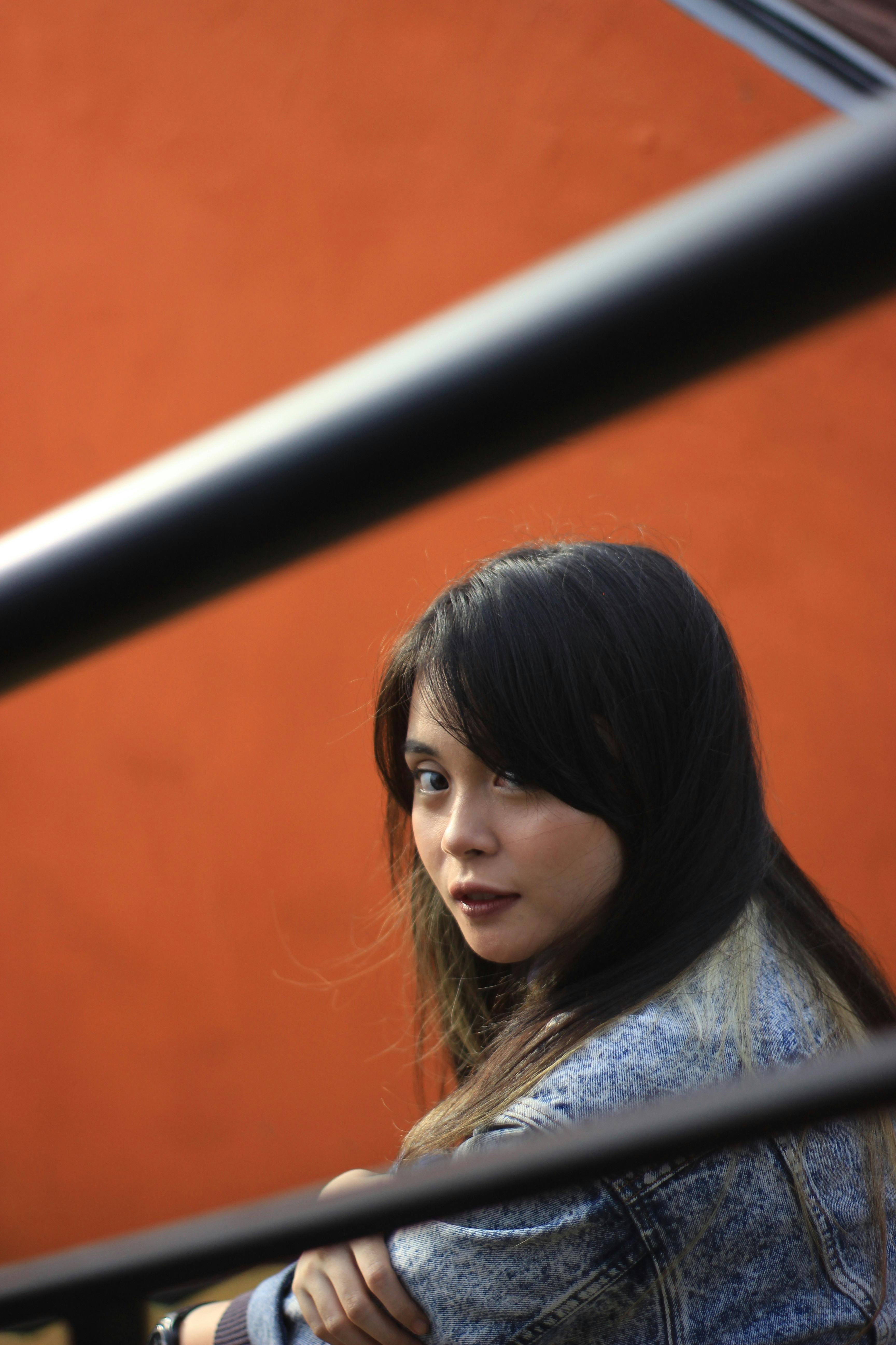 亮橙色墙壁映衬下，一位身着牛仔布的时尚女性肖像散发着现代气息