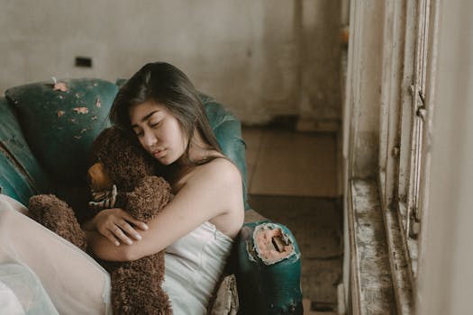 一位沉思的年轻女子抱着泰迪熊，坐在一间饱经风霜的房间里，流露出孤独与沉思