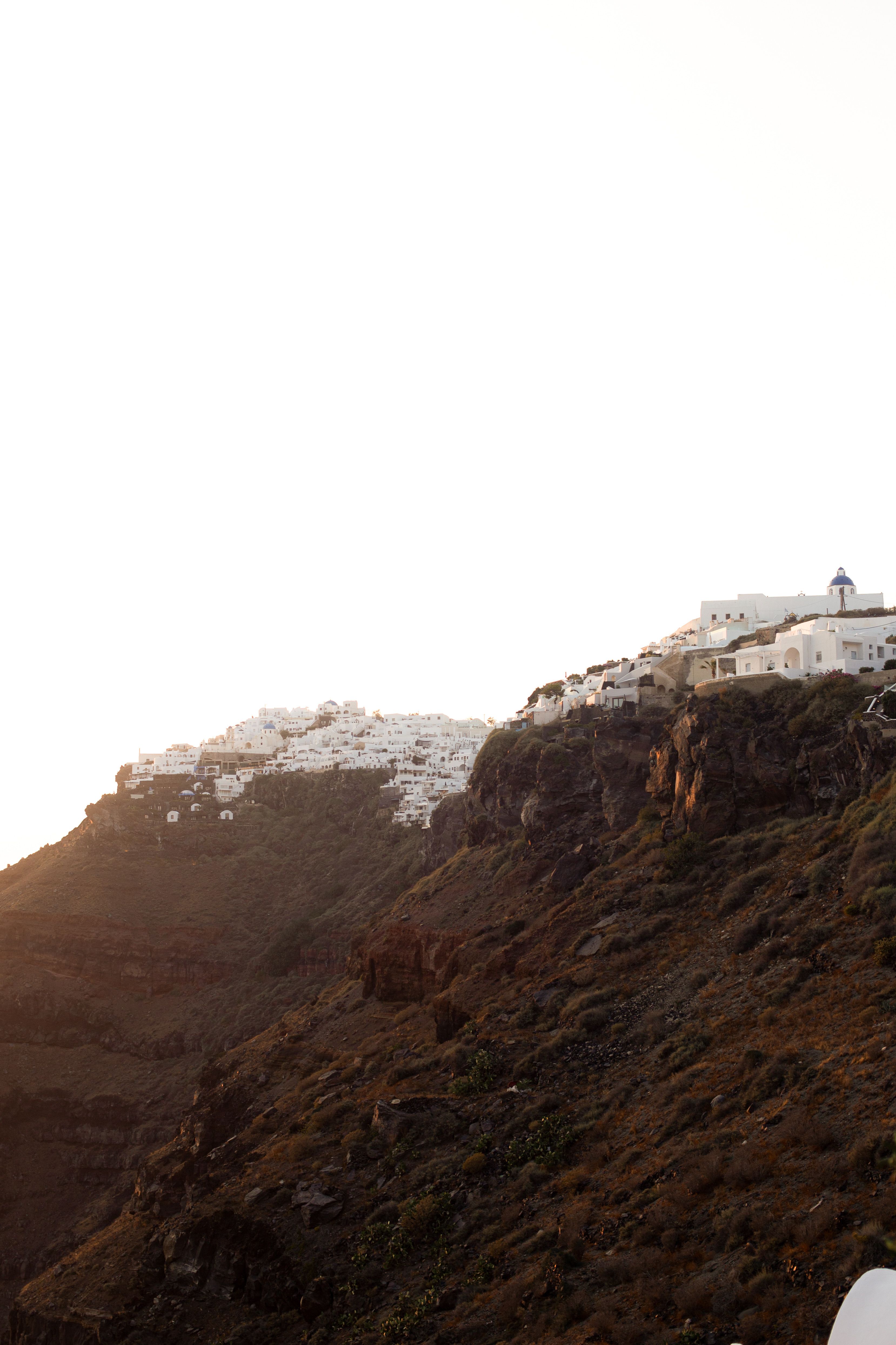 Captivating sunset over Santorini's iconic whitewashed buildings on a rocky cliffside.