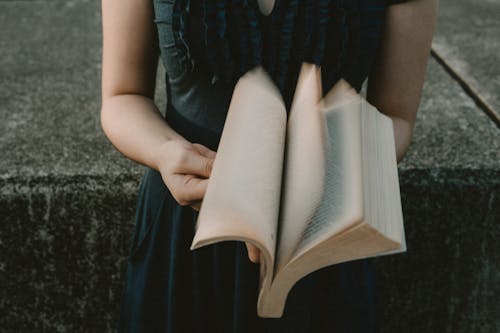 Fotografía De Enfoque Selectivo De Mujer De Pie Hojeando Páginas Del Libro