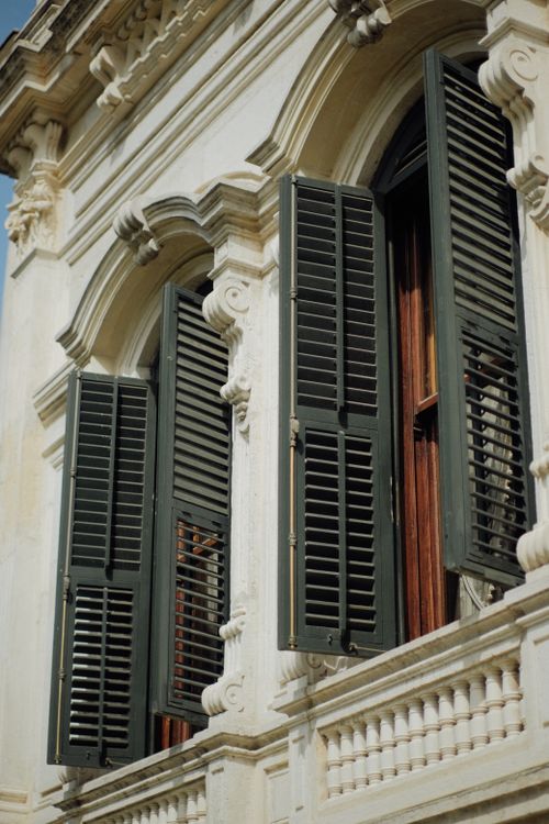 Free Close-up of a vintage building facade with open green shutters, showcasing intricate architectural details. Stock Photo