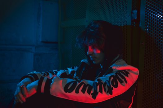 Teenager in dramatic urban setting with moody lighting.