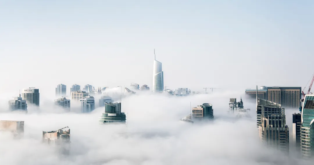 Dubai Marina towers rising above low cloud, where UK and European businesses relocate for a 9% corporate tax
