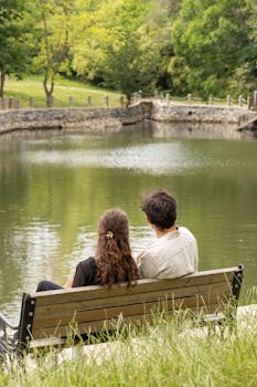 A couple sits on a bench overlooking a tranquil pond in an Istanbul park.