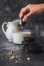Person Holding Piece of Biscuit With Milk in Glass