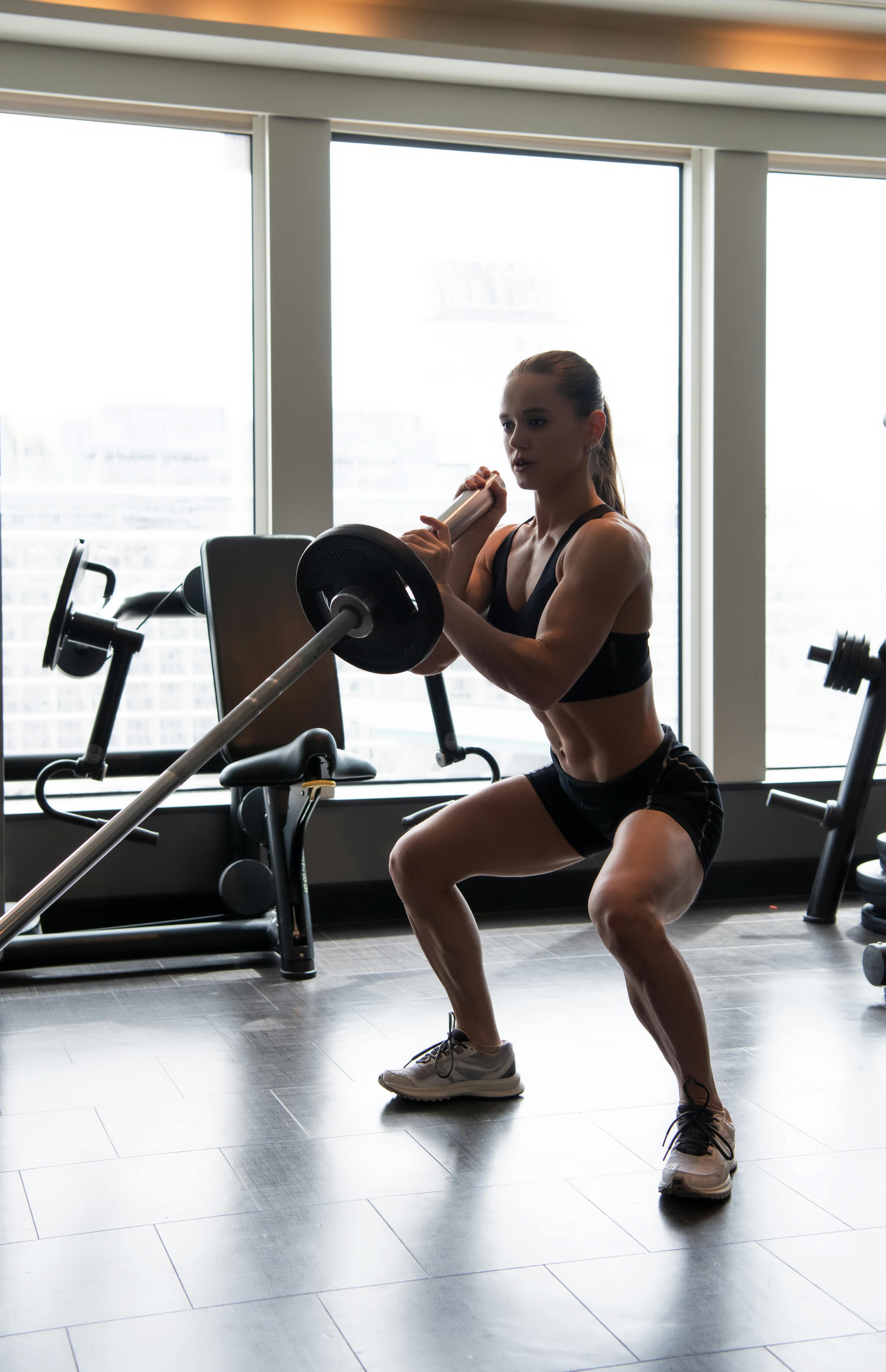 Athlète féminine effectuant un squat avec haltères en salle de musculation