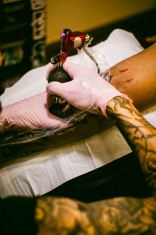 Free Tattoo artist creating intricate design on client's arm in a studio setting, highlighting skilled craftsmanship. Stock Photo