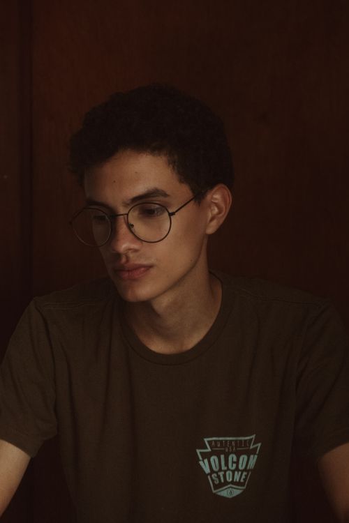 Free Portrait of a young man wearing glasses, deep in thought indoors. Stock Photo
