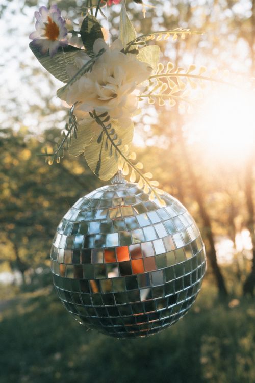 Free A disco ball with flowers reflects sunlight outdoors, creating a vibrant and festive atmosphere. Stock Photo